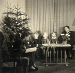 811890 Afbeelding van J.W. Verbeek - Bruschwiler die haar kinderen Jan, Hannie en Lisette voorleest naast de kerstboom ...